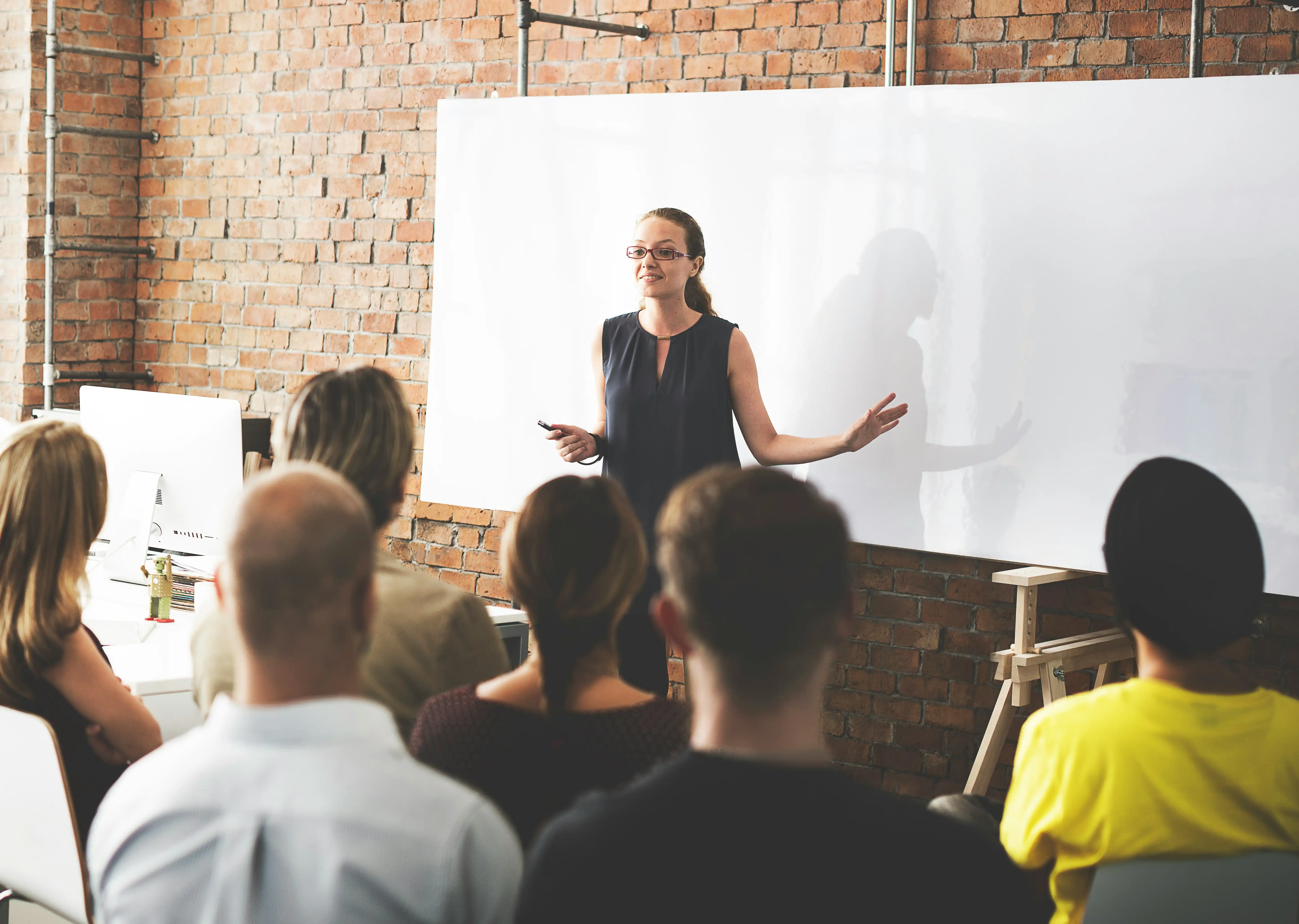 Mediatorin steht vor Whiteboard und spricht zum Team